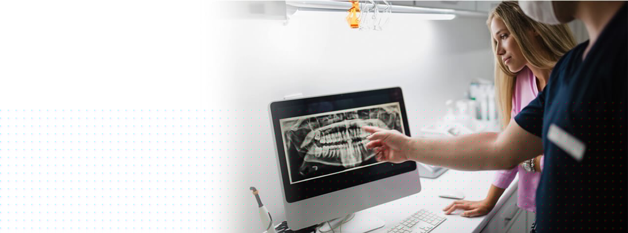 A dental professional wearing safety PPE gear and white lab coat smiling compassionately